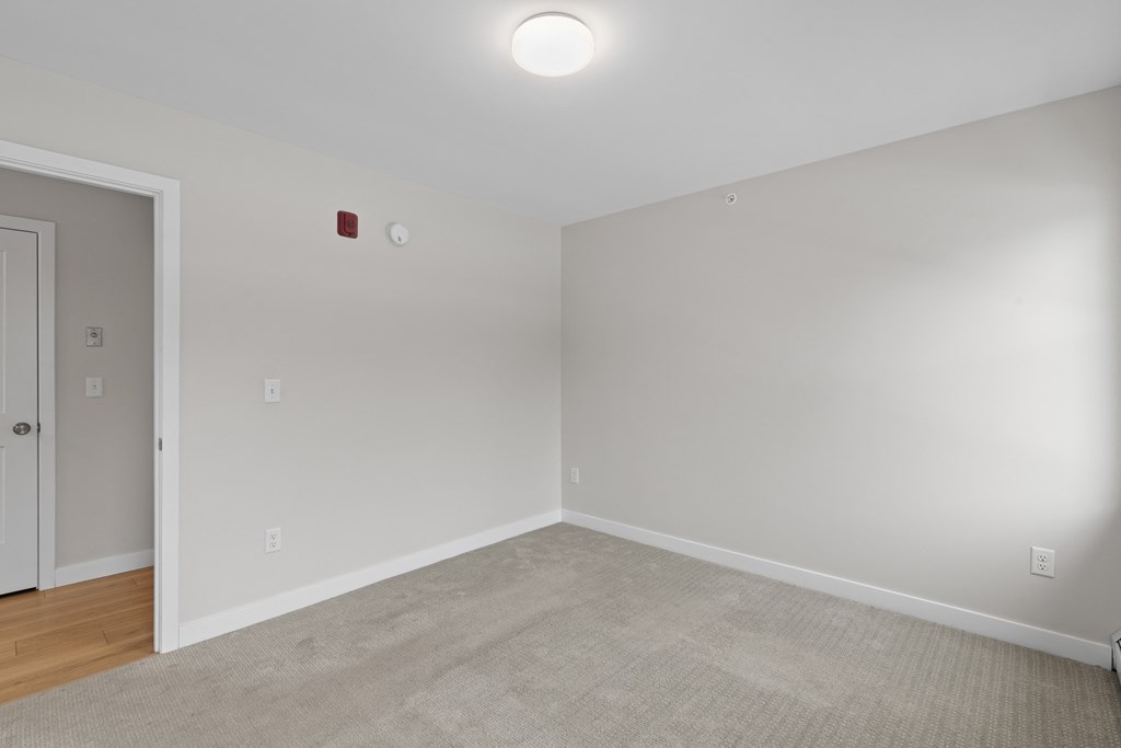 a bedroom with white walls and wood flooring and a white door