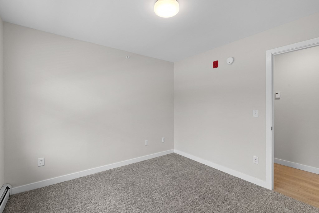 a bedroom with white walls and wood flooring and a white door