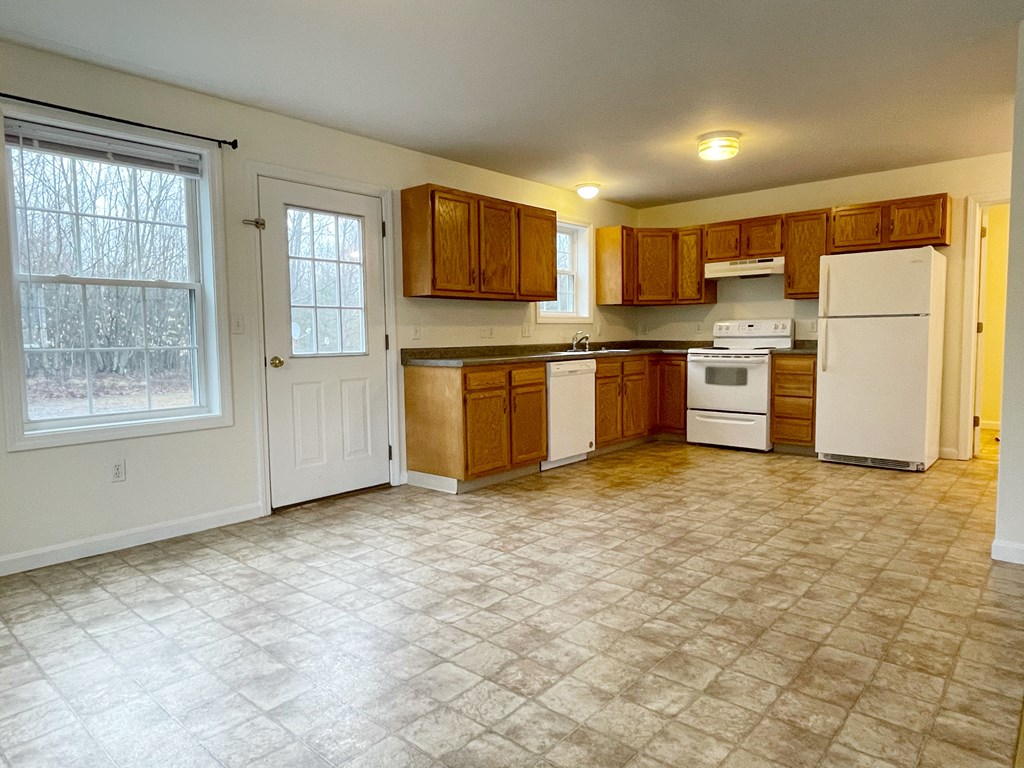 A kitchen with white appliances and wooden cabinets.