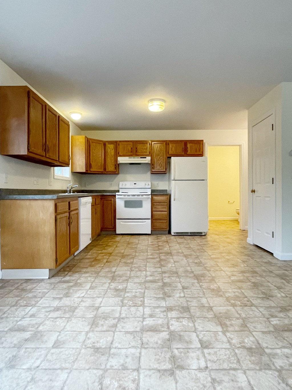 A kitchen with white appliances and wooden cabinets.