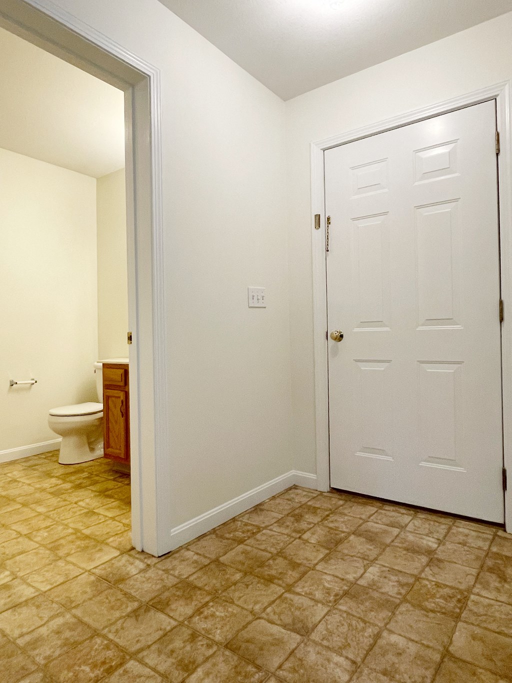 A white door is closed in a room with a tiled floor.