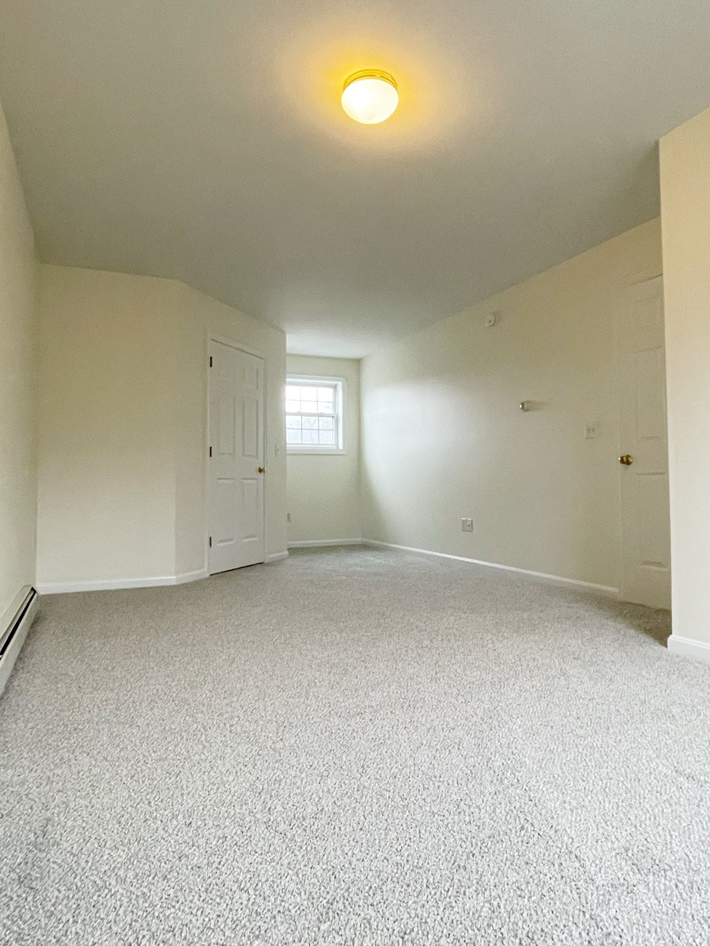A room with a carpeted floor and a window.