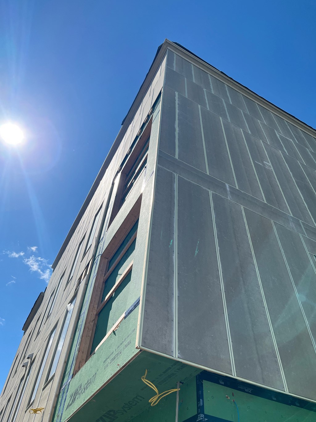 looking up at the corner of a building with the sky and the sun