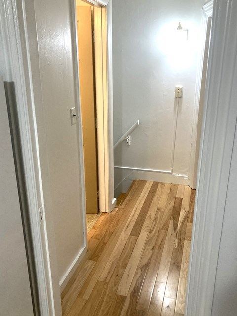 a small hallway with wood flooring and a staircase