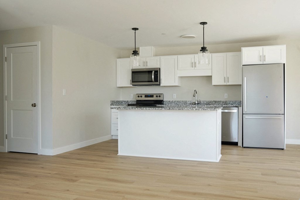 an empty kitchen with white cabinets and a counter top