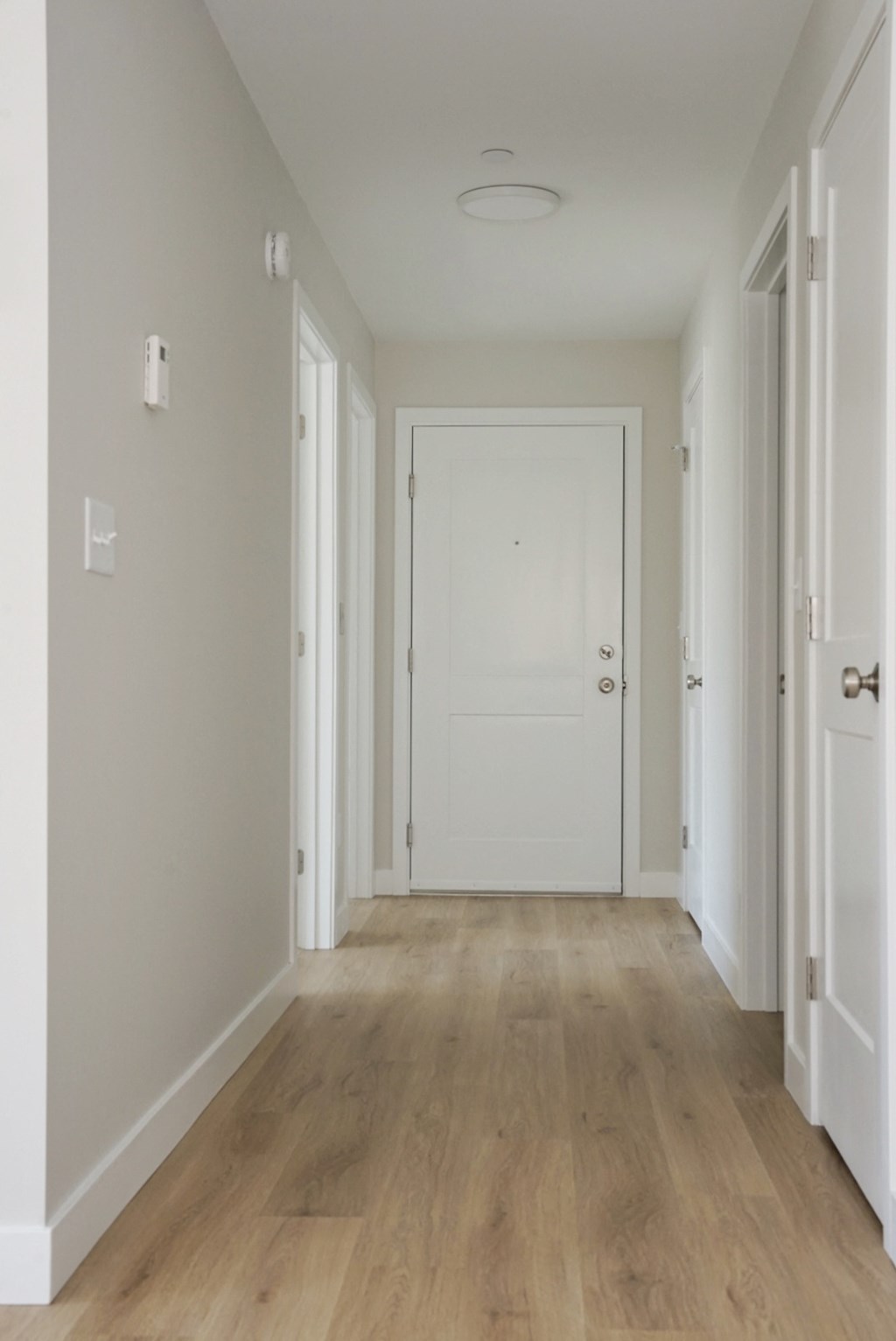 an empty hallway with a white door and wood flooring