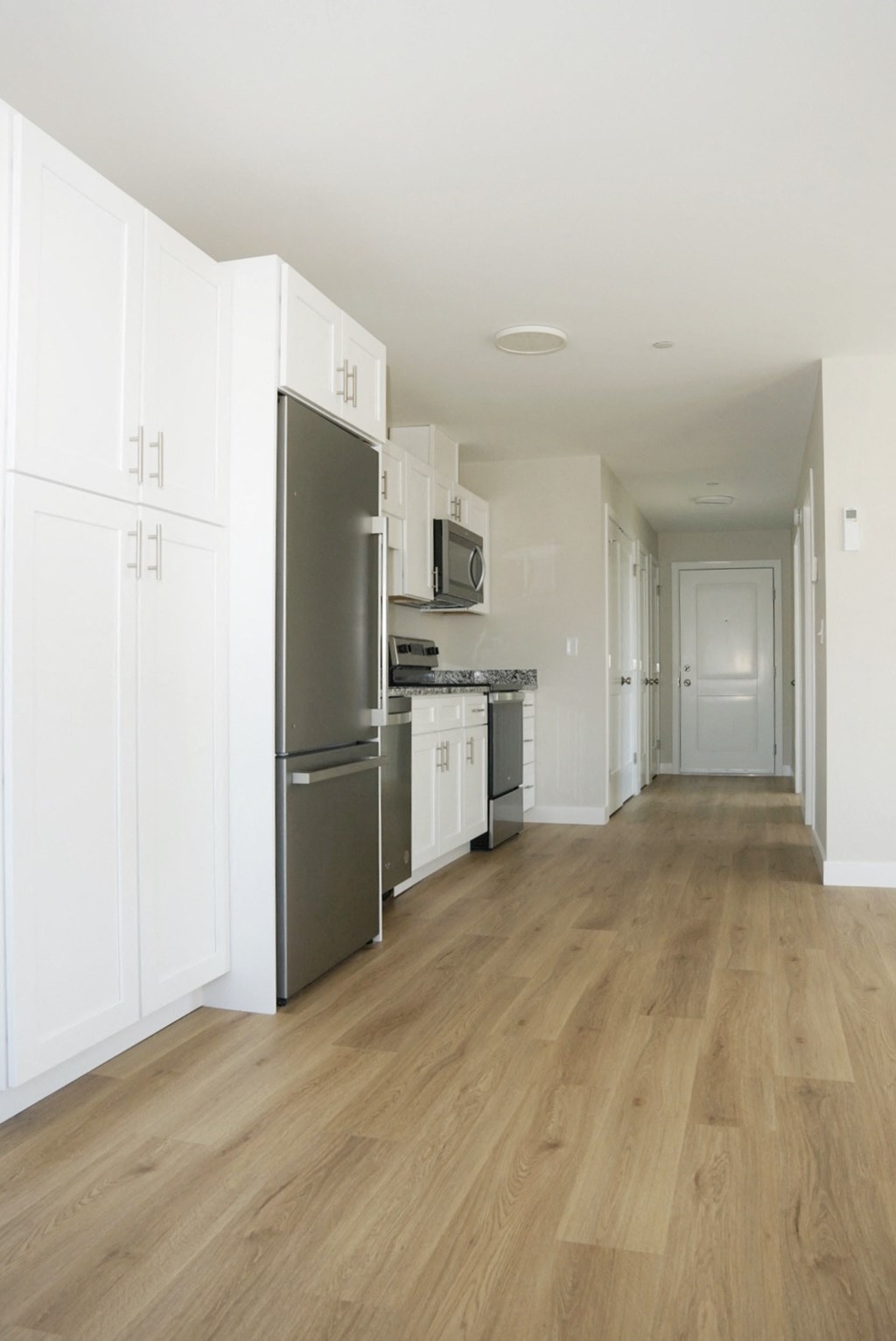 a renovated kitchen with white cabinets and stainless steel appliances and a wooden floor
