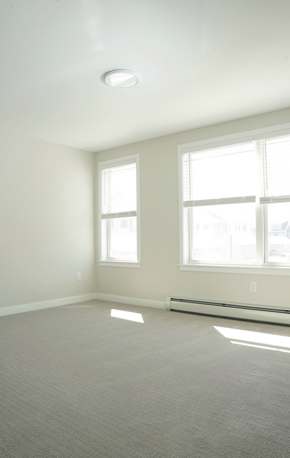 an empty room with two windows and a carpeted floor