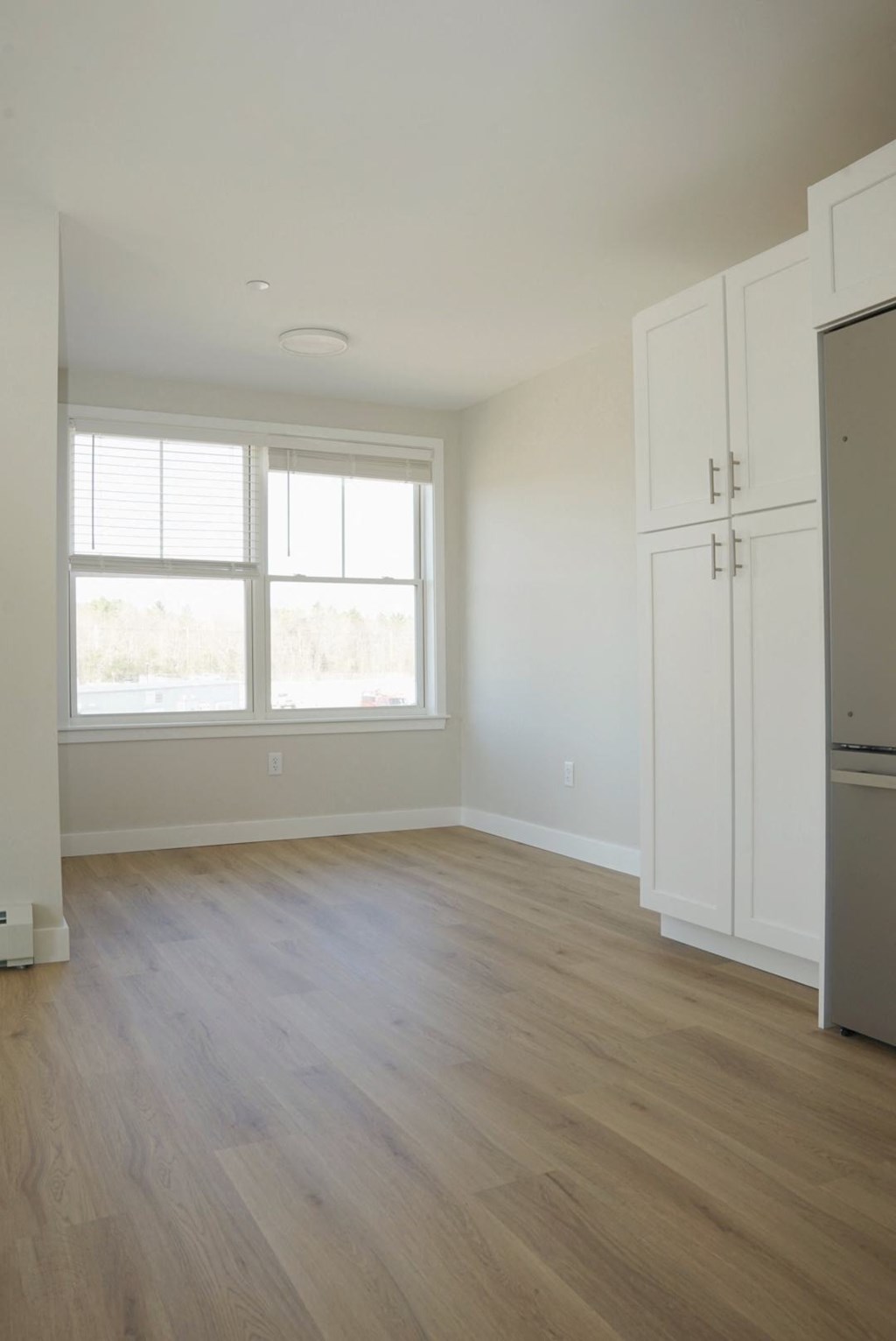an empty living room with white cabinets and a window