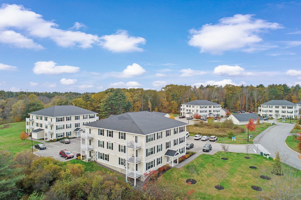 an aerial view of a group of apartment buildings with trees in the background