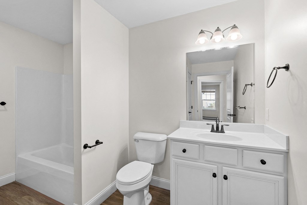 a white bathroom with a white sink and toilet and a shower