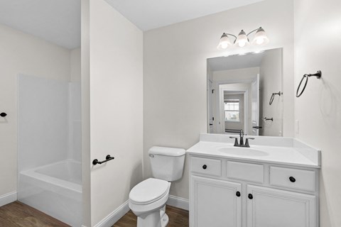 a white bathroom with a white sink and toilet and a shower