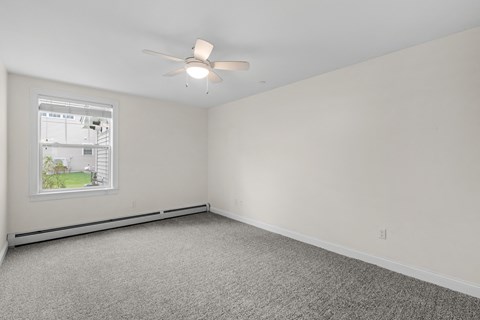 an empty living room with a ceiling fan and a window
