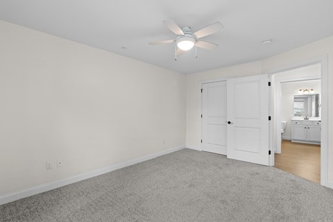 an empty living room with white walls and a ceiling fan
