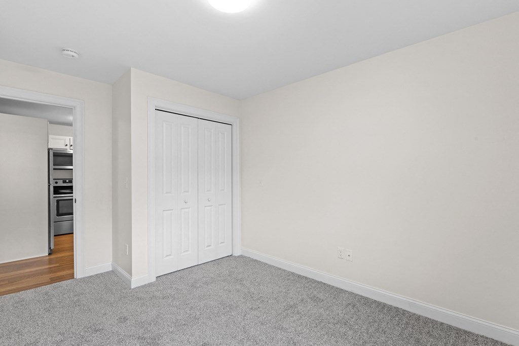 a bedroom with white walls and a door to a closet