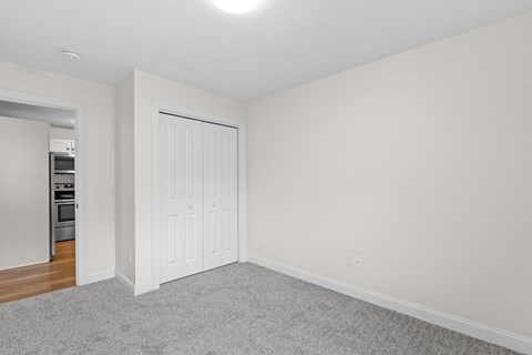 a bedroom with white walls and a door to a closet