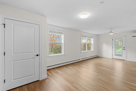 an empty living room with white walls and wood floors and a white door