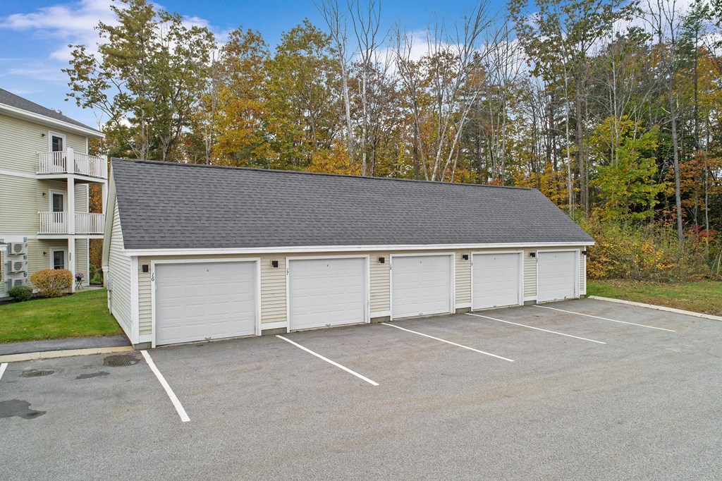a white garage with a gray roof in a parking lot