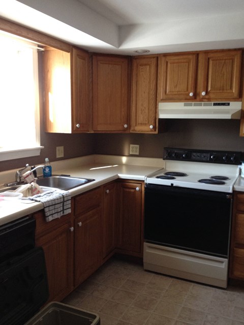 A kitchen with wooden cabinets and a black oven.