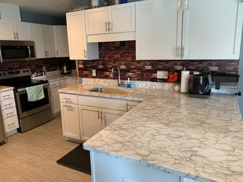 A kitchen with a marble countertop and a brick backsplash.