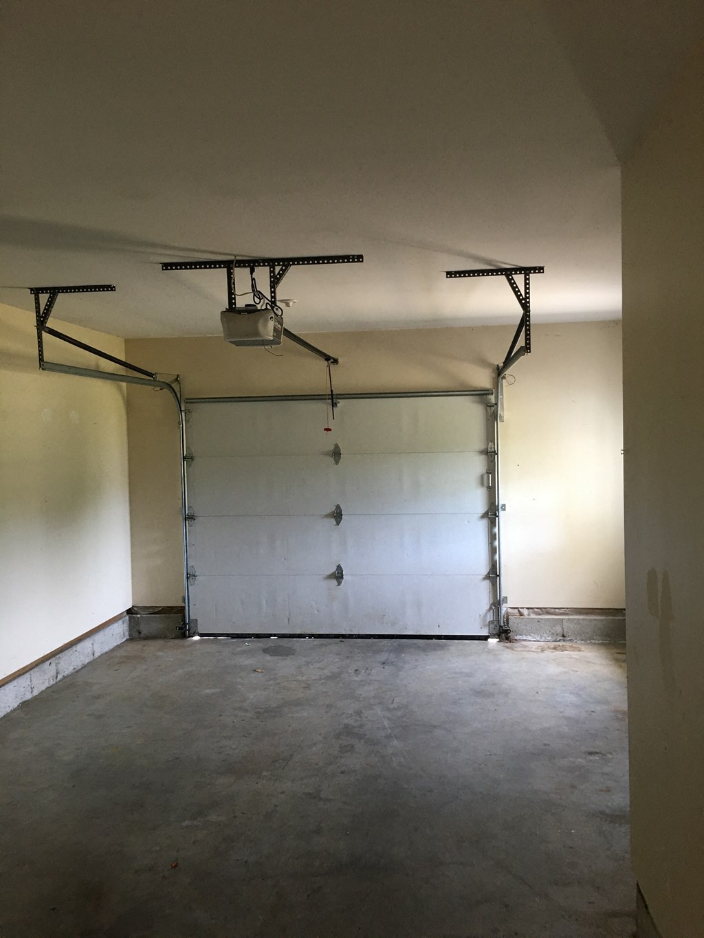 A garage with a white door and a white ceiling with a light fixture.
