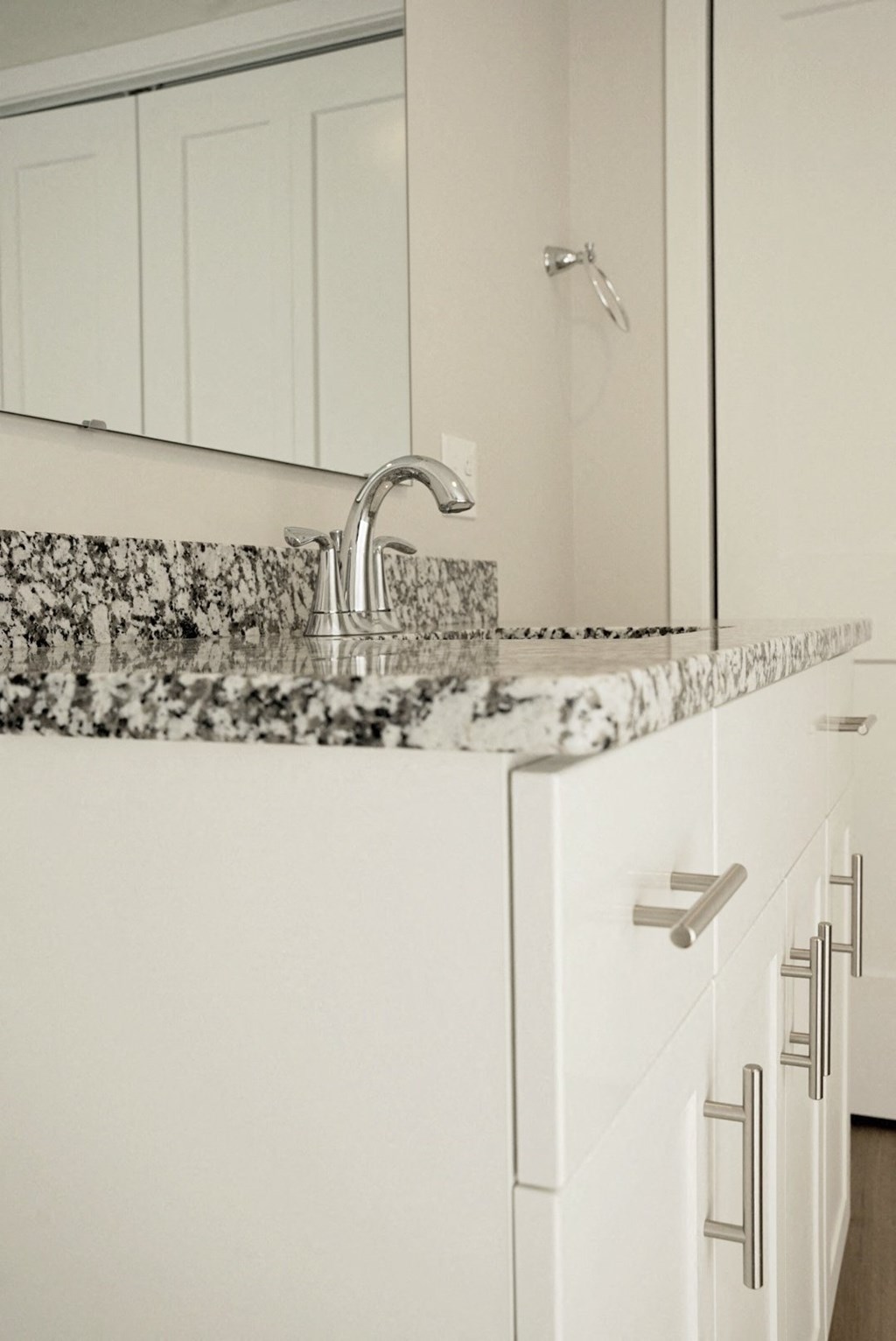 a white kitchen with marble counter tops and a sink