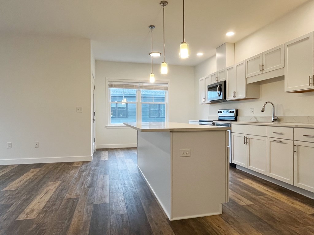 A kitchen with a white island and wooden floors.