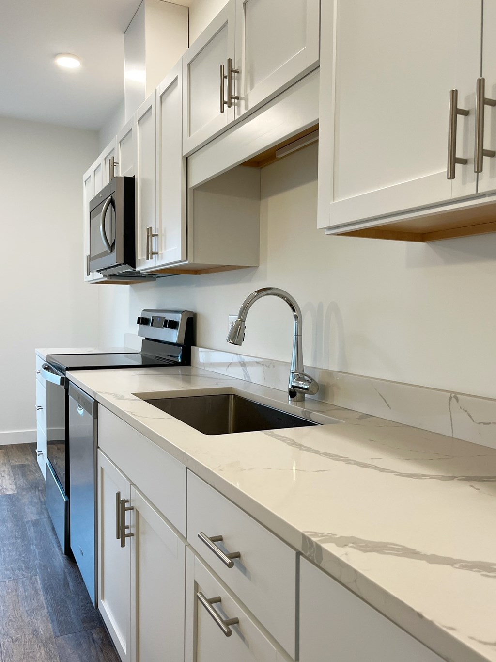 A kitchen with white cabinets and a black microwave.