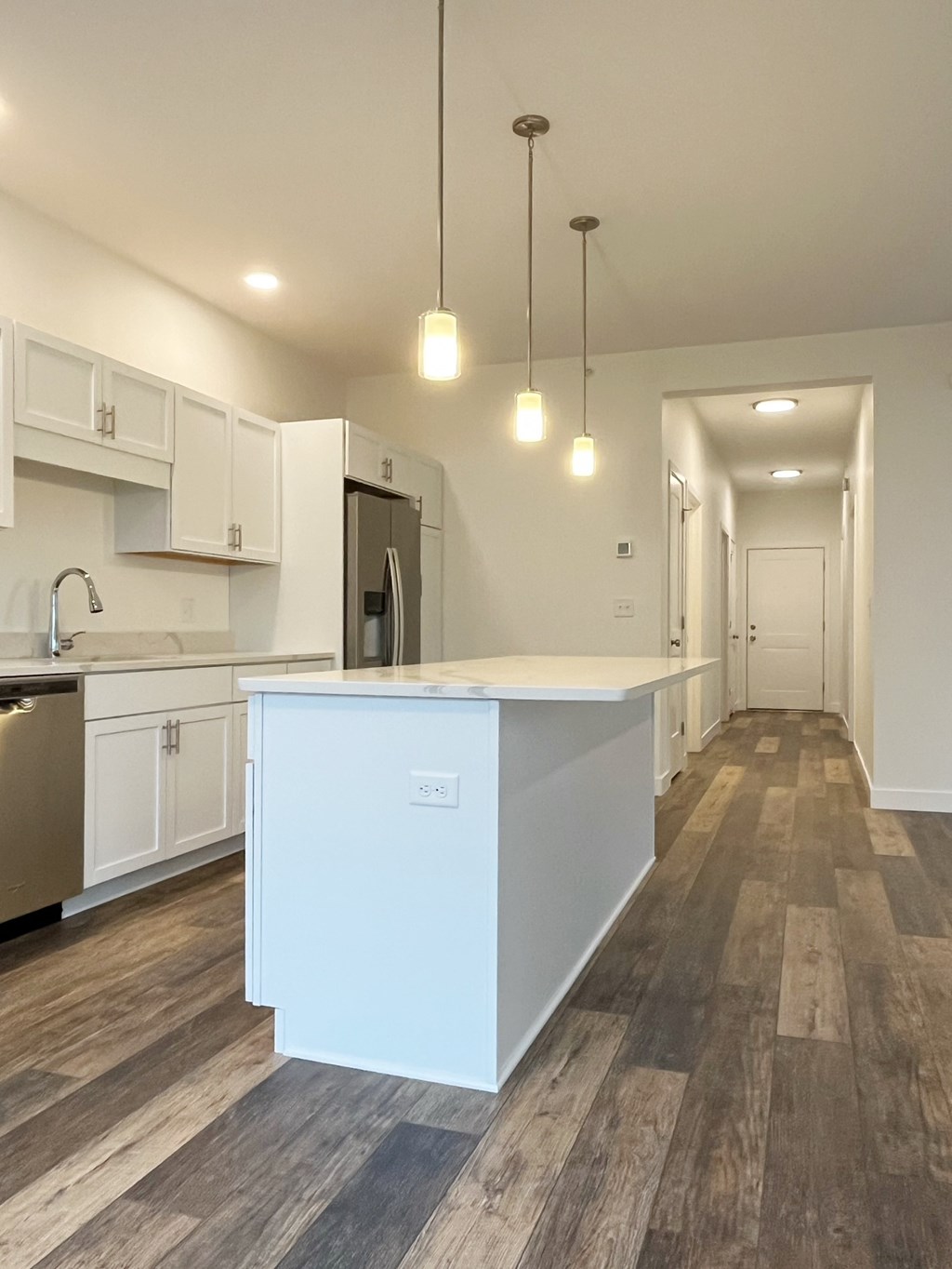 A kitchen with a white island and wooden floors.