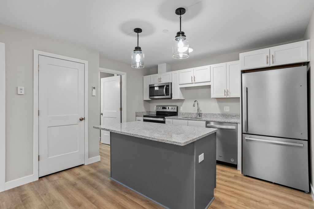 Efficient kitchen with full appliance package, granite island, and ample storage.