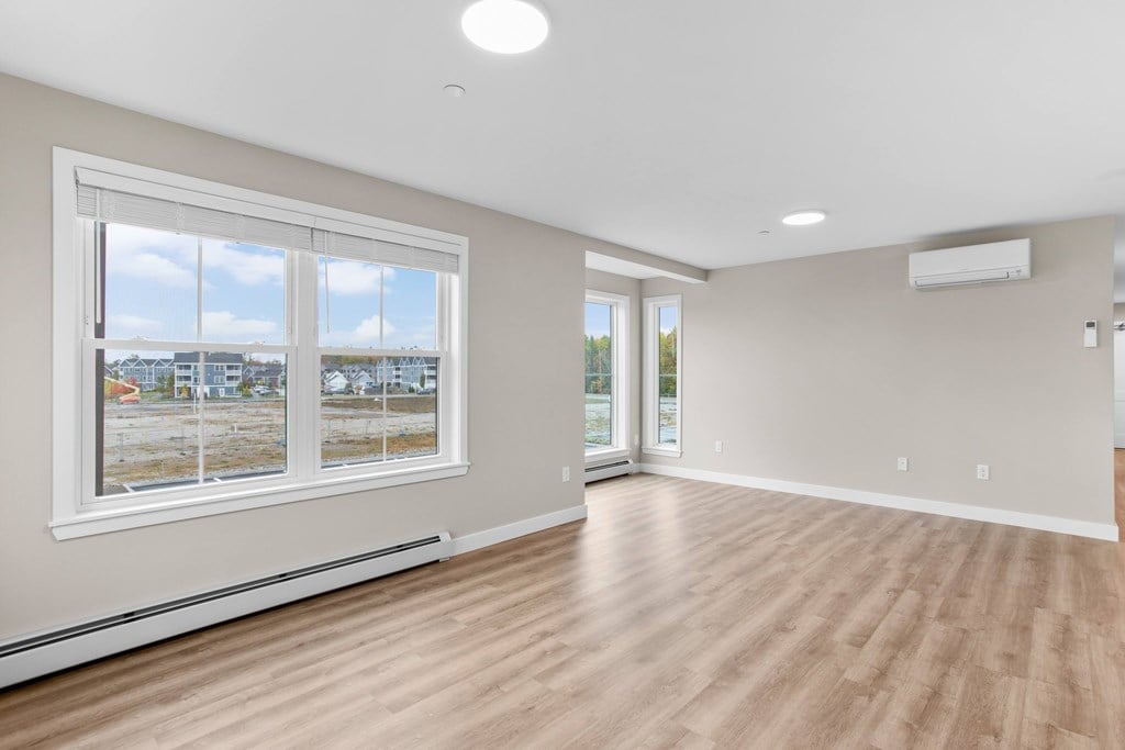 Bright living room with LVP flooring, large windows, and modern climate control.