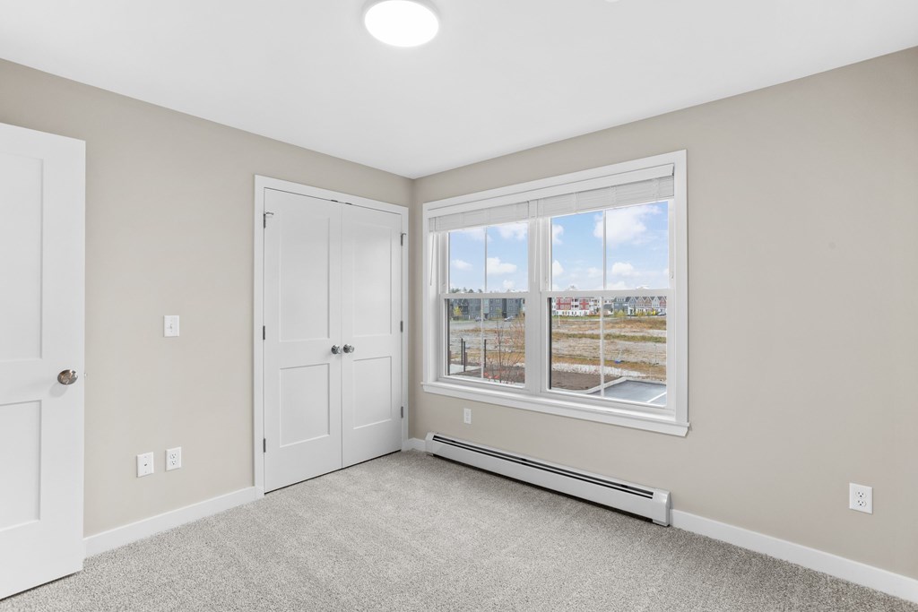 Spacious bedroom with plush carpeting, generous closet space, and natural light from a large window.