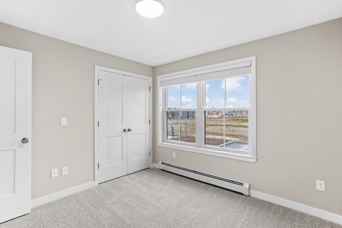 Spacious bedroom with plush carpeting, generous closet space, and natural light from a large window.