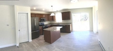A kitchen with a white door and a brown island.