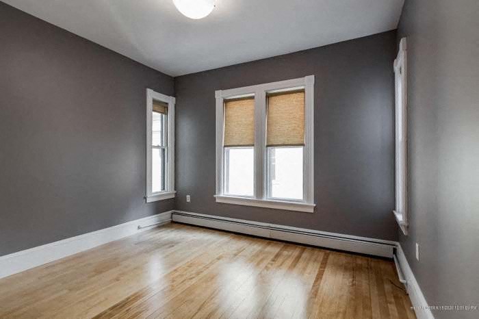 an empty room with a wood floor and two windows