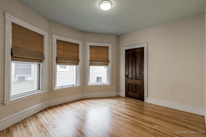 an empty living room with a wood floor and three windows
