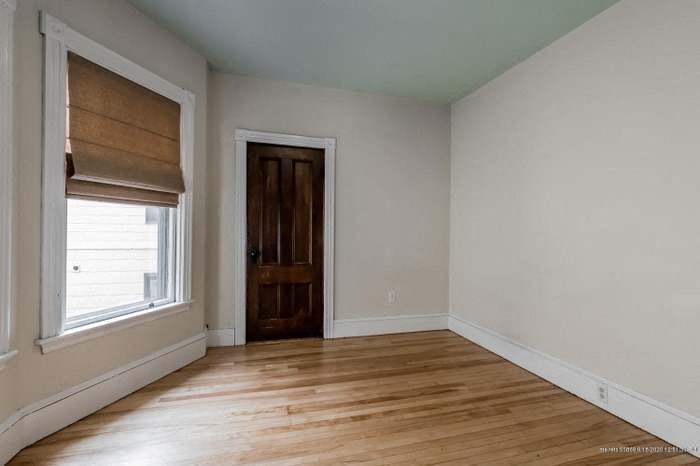 an empty room with wooden floors and a window and a door