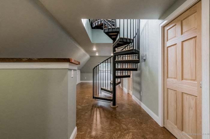 a hallway with a spiral staircase and a wooden door
