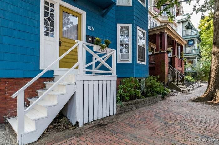 a blue house with stairs and a brick sidewalk