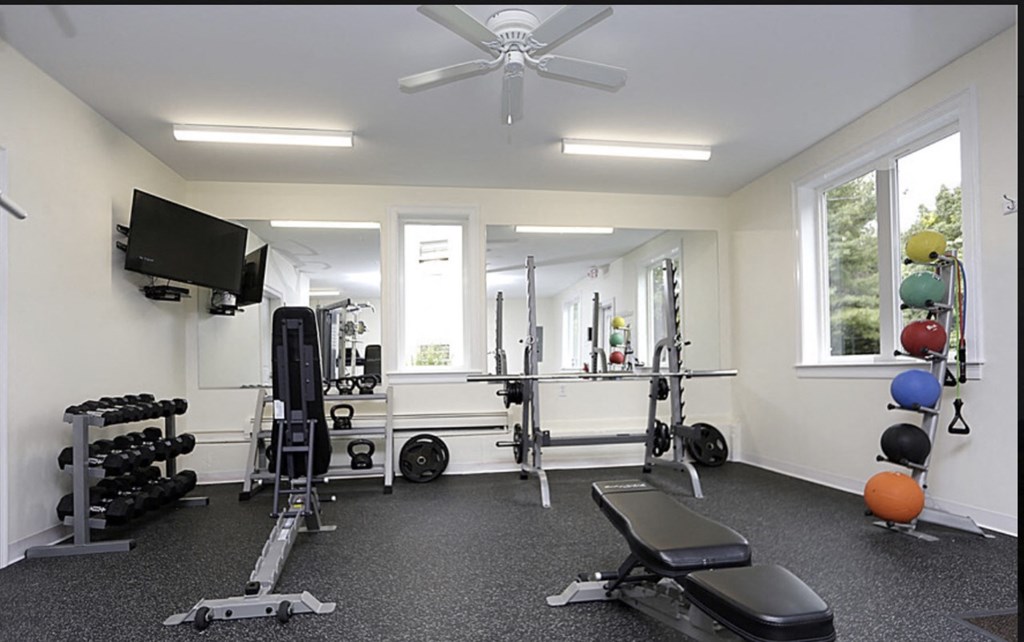 a home gym with exercise equipment and a ceiling fan