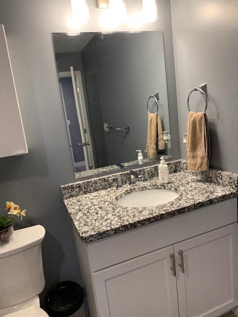 A bathroom with a toilet, sink, and mirror.