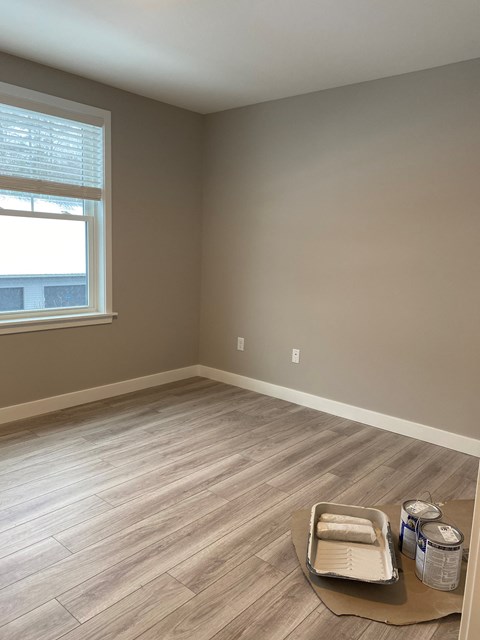 A room with a window and wooden flooring is being painted.