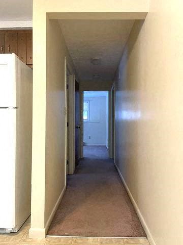 a long hallway with a refrigerator and a door