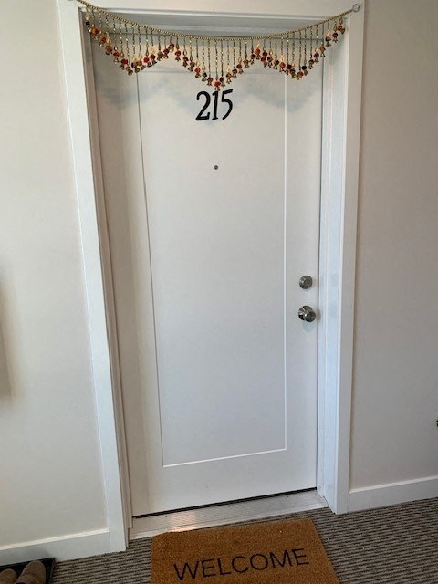 A white door with a number 215 and a welcome mat below it.