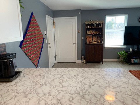 A room with a bed in the foreground and a wall hanging on the left.