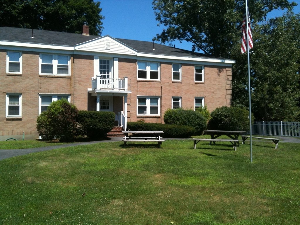 the front of a brick building with a picnic table and an flag