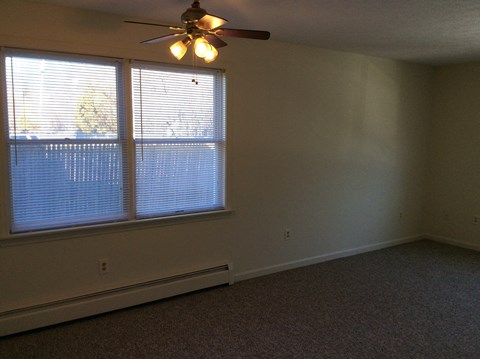 A room with a ceiling fan and a window with blinds.