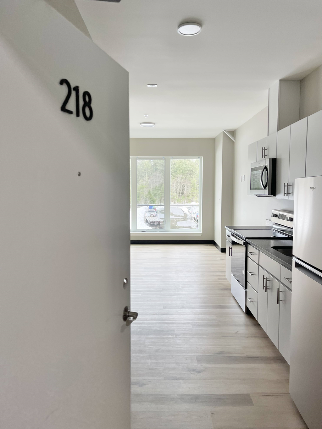 a kitchen with white cabinets and white appliances and a door with a number on it