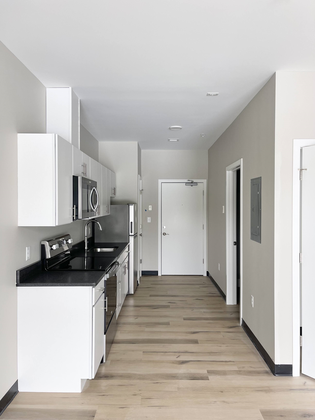 an empty kitchen with white cabinets and black counter tops
