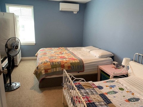 A bedroom with two beds and a fan.